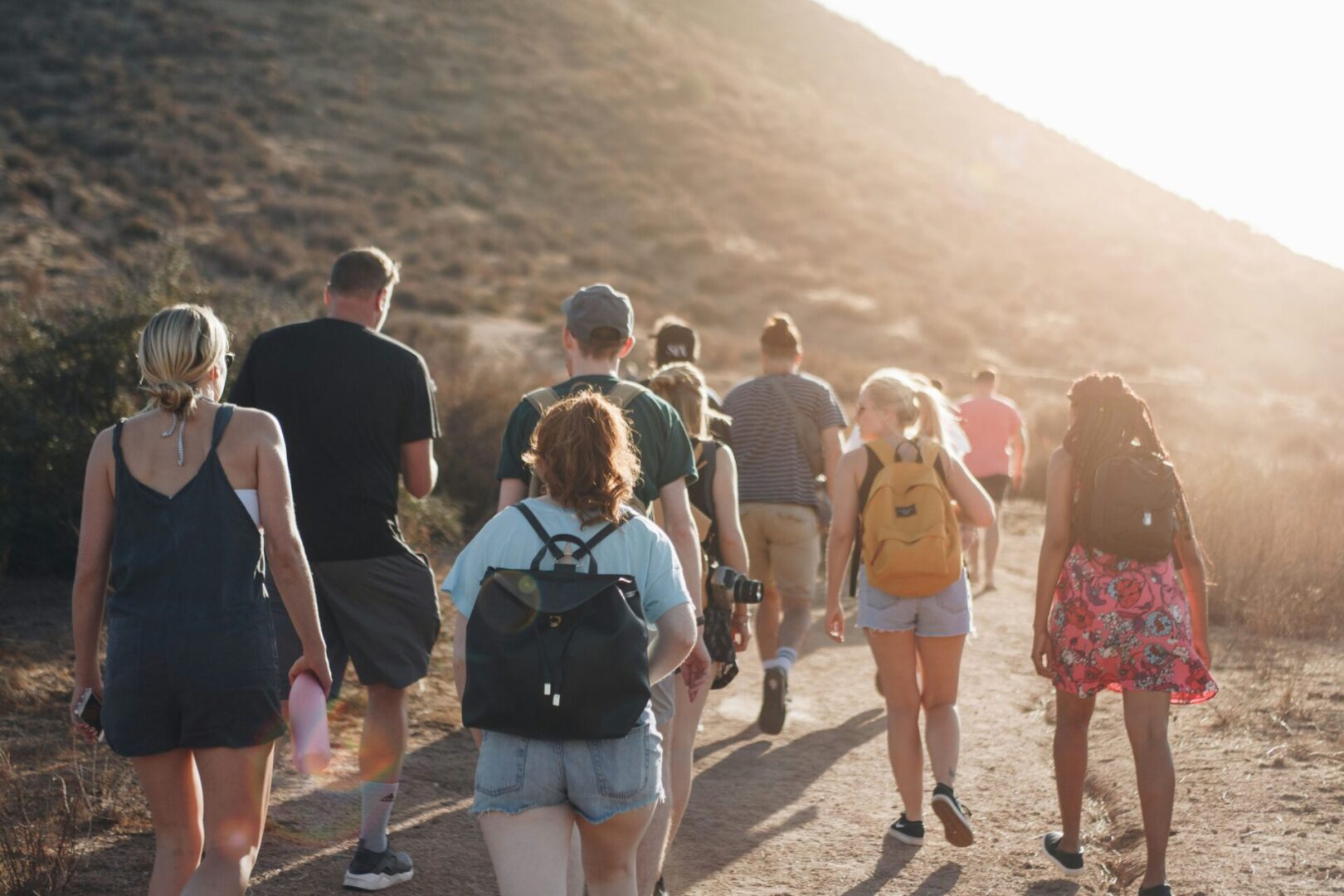 luke-porter-NEqEC7qa9FM-unsplash A group of people walking down the side of a hill.